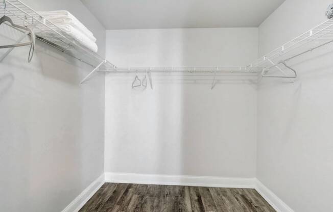 an empty closet with white walls and a wood floor