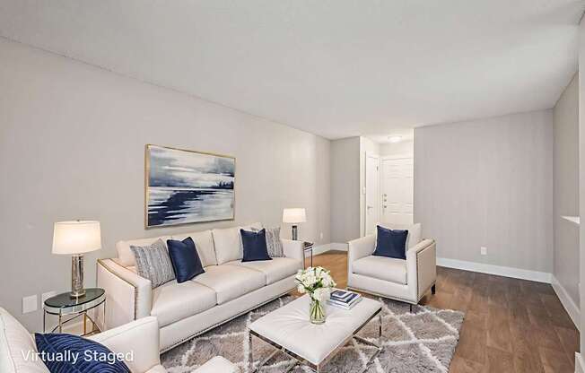 A living room with a white couch, a coffee table, and a painting on the wall.
