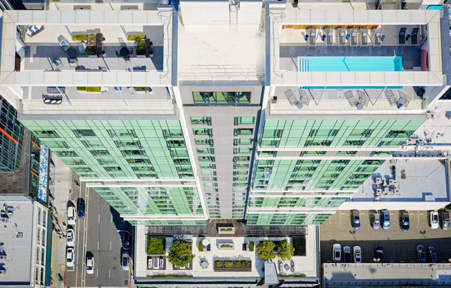 A modern building with a glass facade and a pool on the top floor.