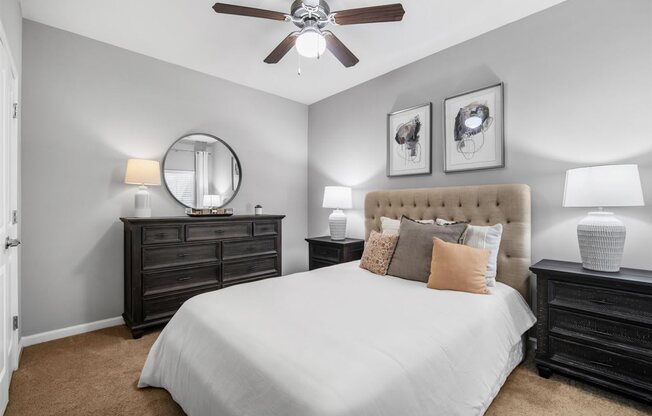 A bedroom with a large bed, a dresser, and a ceiling fan.