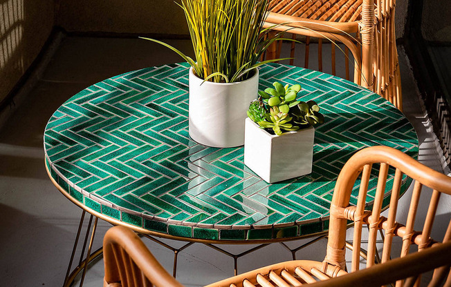 A table with a plant on it and two chairs.