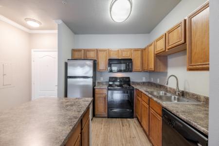A kitchen with a black stove top oven and wooden cabinets.