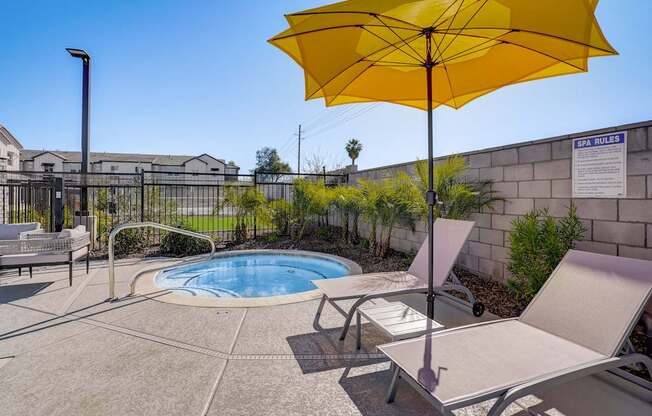 A yellow umbrella is in front of a pool.