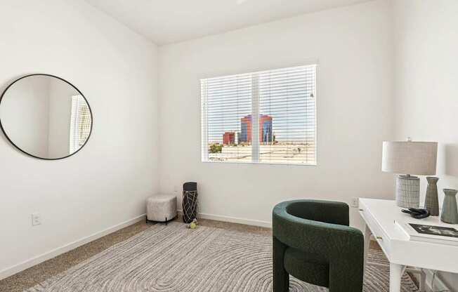 A room with a green chair, a white table, and a round mirror on the wall.