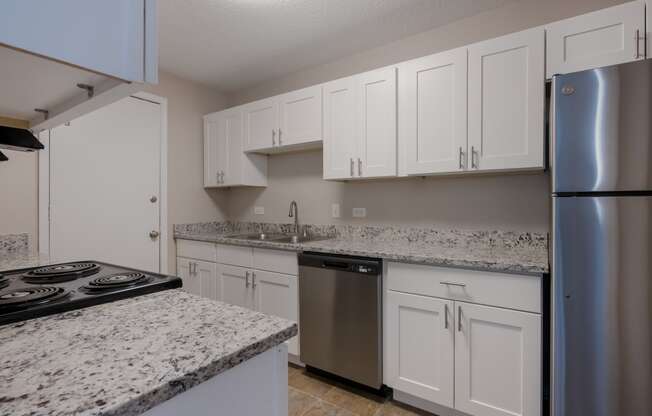 a kitchen with white cabinets and granite counter tops and stainless steel appliances