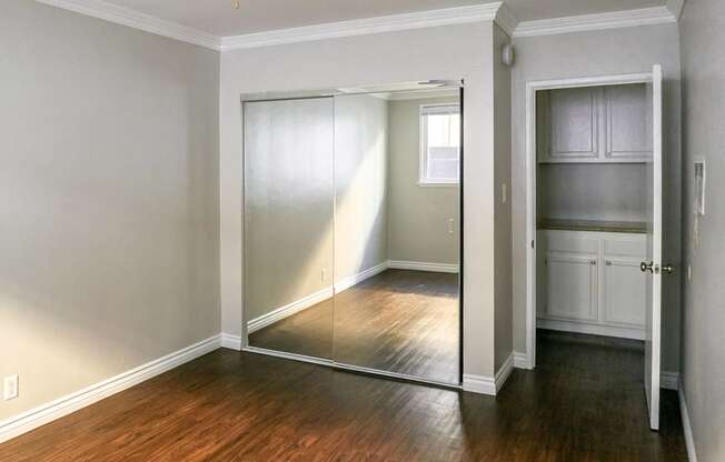 a bedroom with a mirrored closet door and a hard wood floor