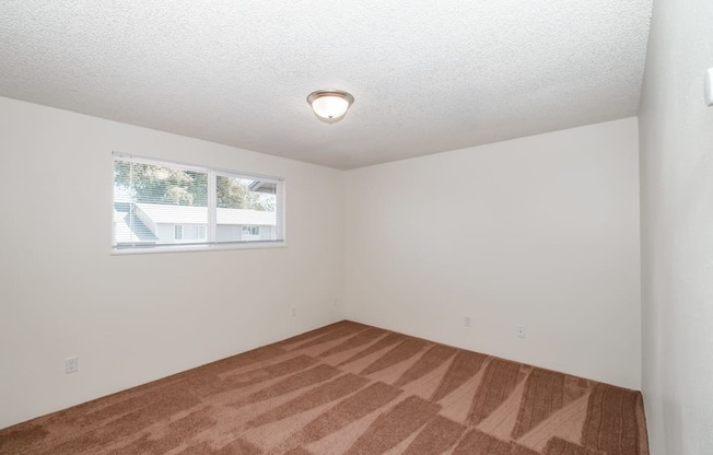 a bedroom with white walls and a window