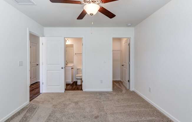 Townhouses For Rent In North Charleston, SC - Highland Townhomes - Spacious Bedroom With Plush Carpeting, Ceiling Fan, Walk-In Closet, And Bathroom