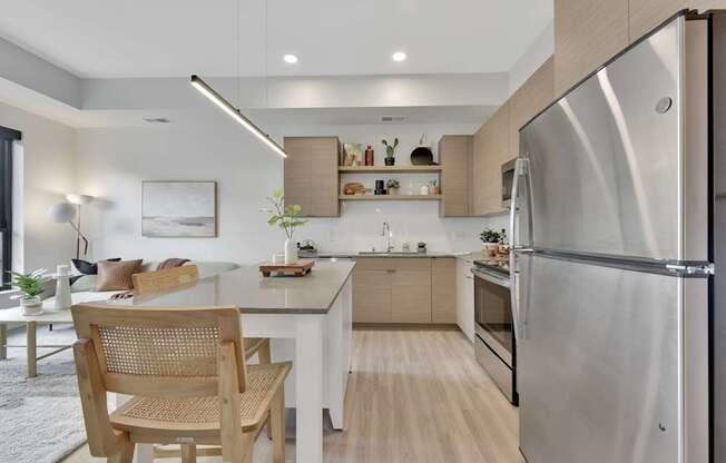A modern kitchen with a stainless steel refrigerator and wooden chairs.