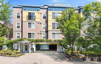 an apartment building with a driveway and trees in front of it at Sir Gallahad Apartment Homes, Bellevue, WA