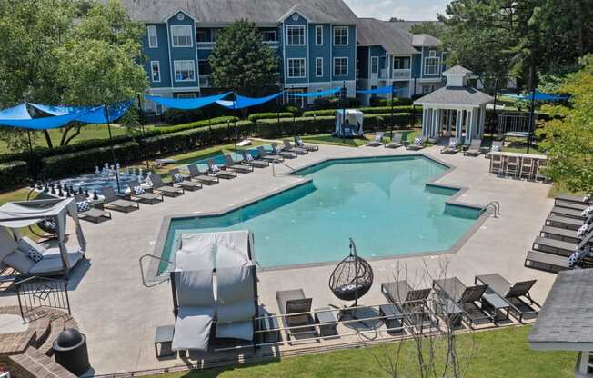 an aerial view of a resort style pool with lounge chairs and umbrellas