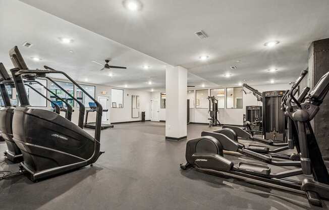 A gym with treadmills, elliptical machines, and a fan.