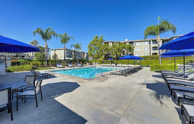 A pool area with tables and chairs and umbrellas.