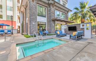 a swimming pool with chairs and a building with a fireplace at Metro Gateway, Riverside, CA, 92503