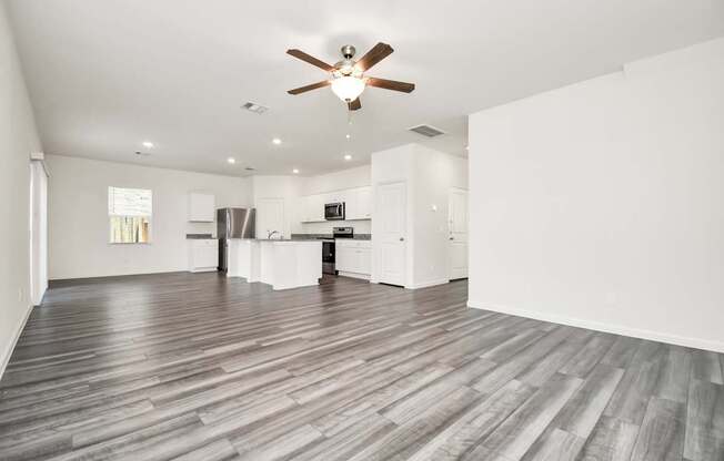 A spacious room with a ceiling fan and wooden flooring.