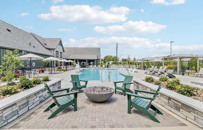 a swimming pool with green chairs and a fire pit at The Depot Raymore, MO 64083