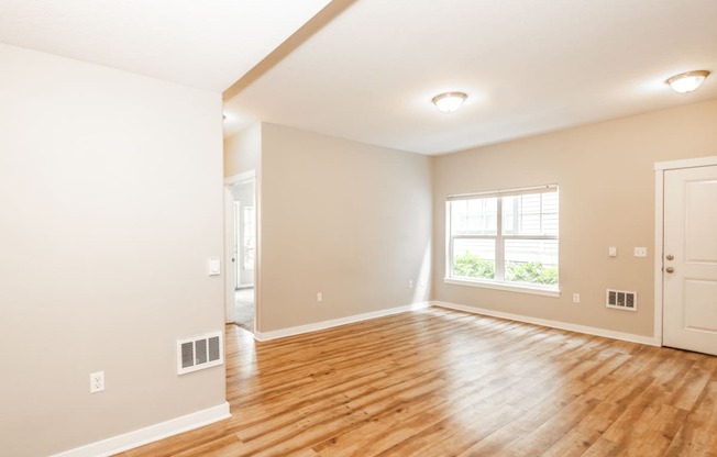 an empty living room with a hard wood floor and a window