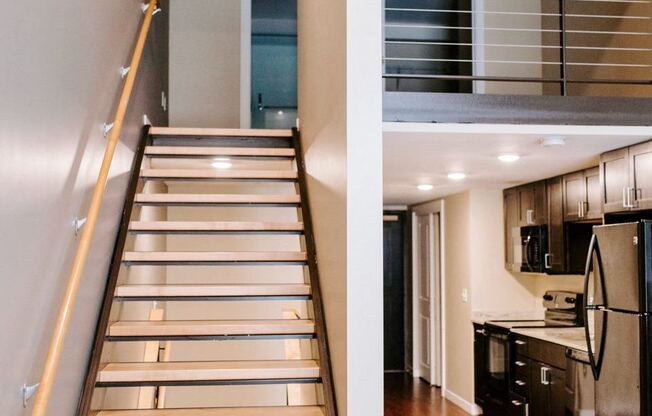 a set of stairs with a railing and a kitchen in a house
