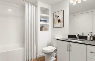 A white bathroom with a toilet, sink, and shower curtain.