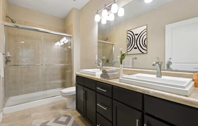 Bathroom with glass shower and double sink at The Amalfi Clearwater Apartments