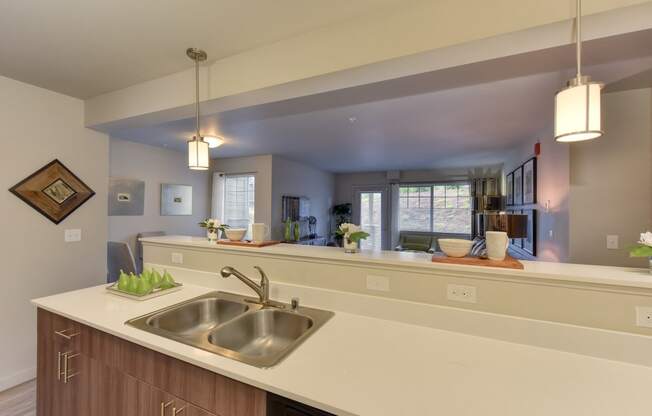 Model Kitchen with View of Living Room, Sink Counter Top, and Hanging Lights