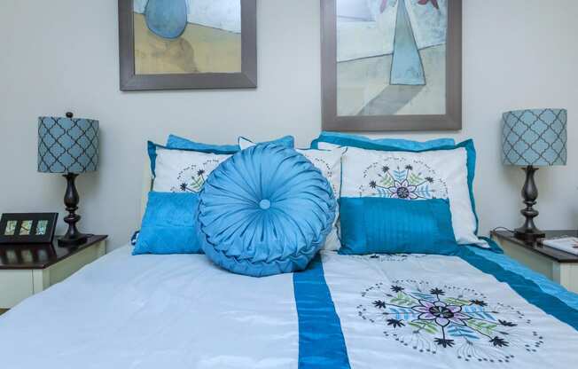the master bedroom has a large bed with blue pillows and art on the wall