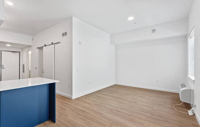 an empty living room and kitchen with white walls and wood floors