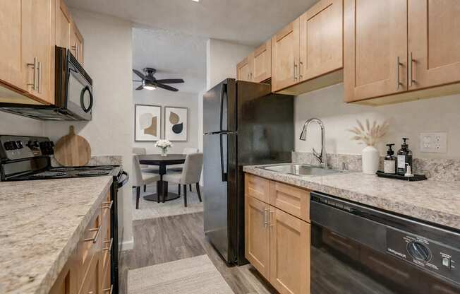 A kitchen with a black refrigerator and wooden cabinets.