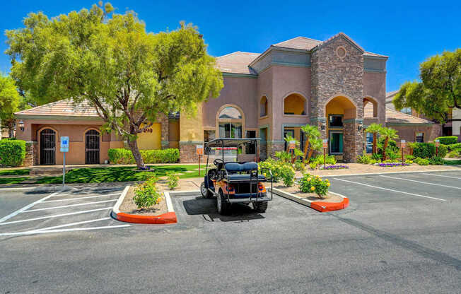 A black golf cart is parked in a parking lot in front of a building.