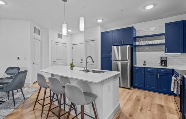 a kitchen with blue cabinets and a white counter top and a stainless steel refrigerator