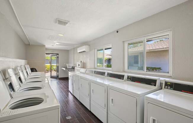 A row of washing machines are lined up in a laundry room.