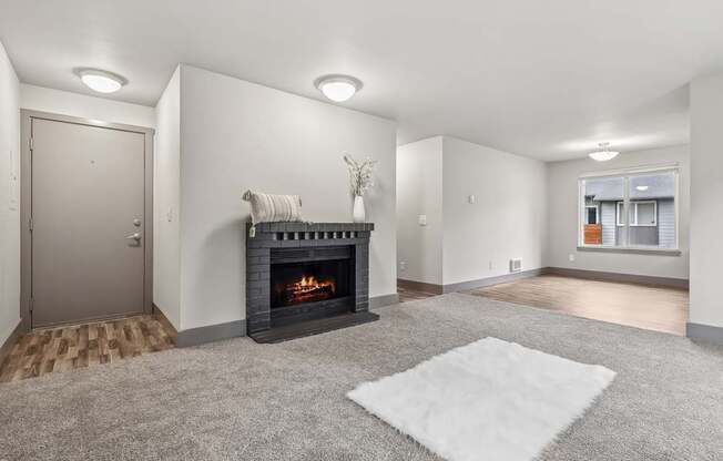 A living room with a fireplace and a rug on the floor.
