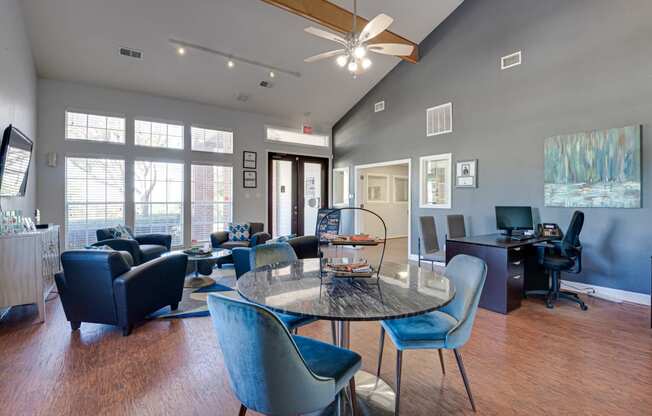 a living room with a round table and chairs and a desk with a computer