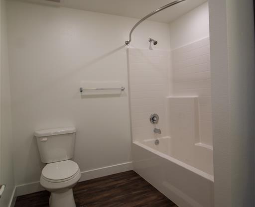 a white toilet sitting next to a bath tub at Loma Villas Apartments, San Bernardino