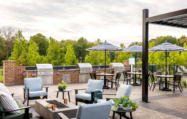 A patio with chairs and umbrellas overlooking a forest.