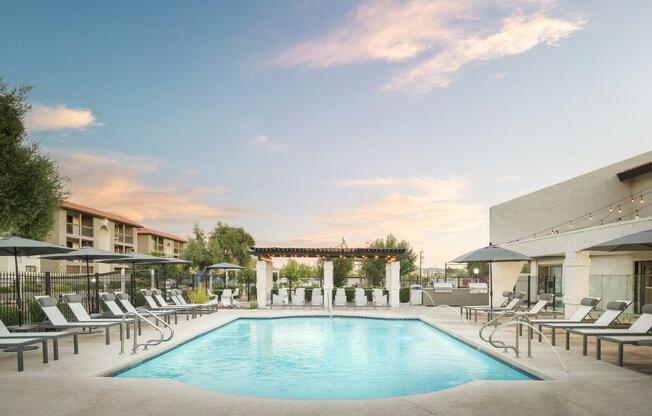 a swimming pool at a hotel with chairs and umbrellas