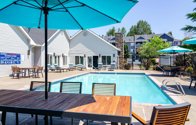 a resort style swimming pool with patio table and an umbrella at The Arden Apartments, Gresham Oregon