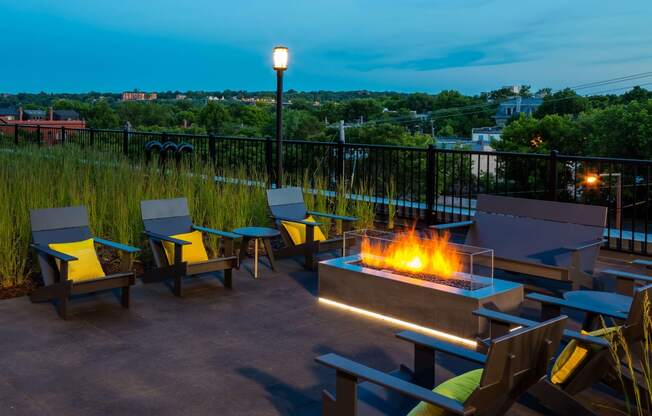 Outdoor fireplace at night with lounge chairs all looking out onto gorgeous St. Paul.