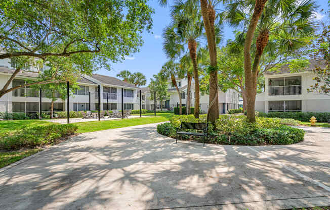 a courtyard with trees and a bench in front of a building