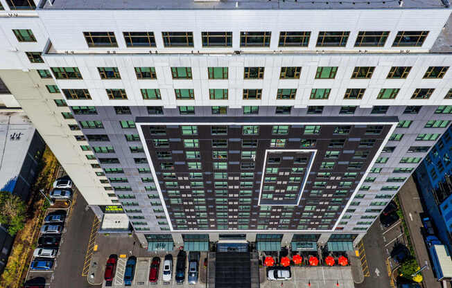 A tall building with a lot of windows and a parking lot in front.