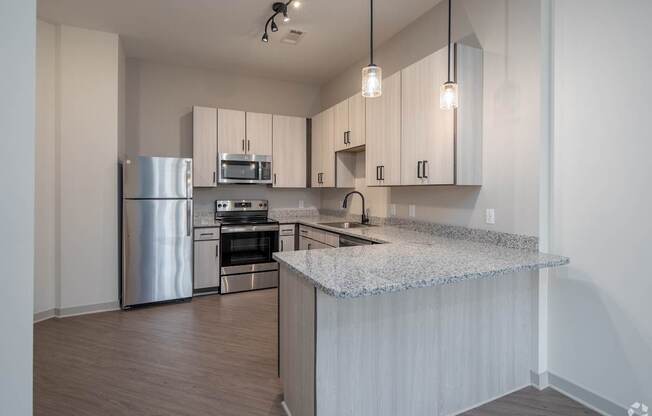A kitchen with a stainless steel refrigerator, microwave, oven, and sink.
