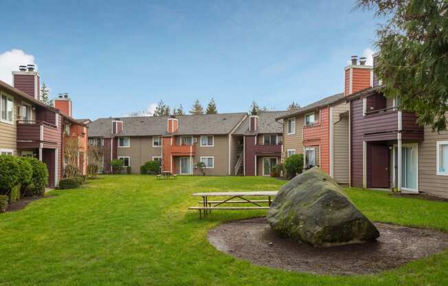 a park with a picnic table and a rock in the grass at Quartz Creek, Mountlake Terrace, Washington