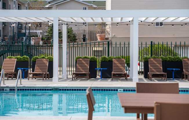 a swimming pool with chairs and a table under a canopy