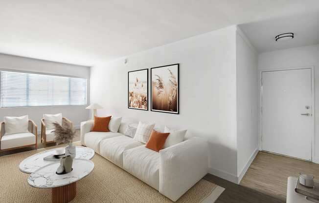 A living room with a white couch and two chairs.