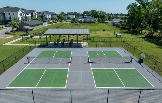 A tennis court with a green surface and a black fence surrounding it.