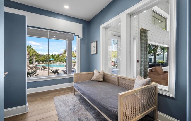 A bedroom with a bed, a window with a view of the pool and trees, and a picture on the wall.