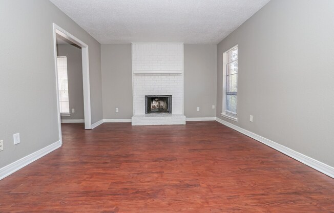 A living room with a fireplace and wood flooring at Magnolia Apartments in Shreveport, LA