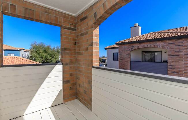 A balcony with a white railing and a brick chimney on a house.
