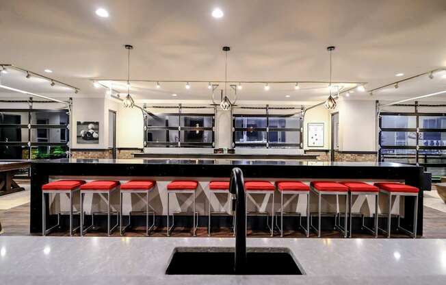 a large kitchen with a long bar with red stools