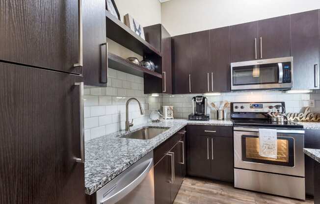 Westwood Green Apartments Kitchen with stainless appliances, grey quarts countertops, and white subway tile backsplash